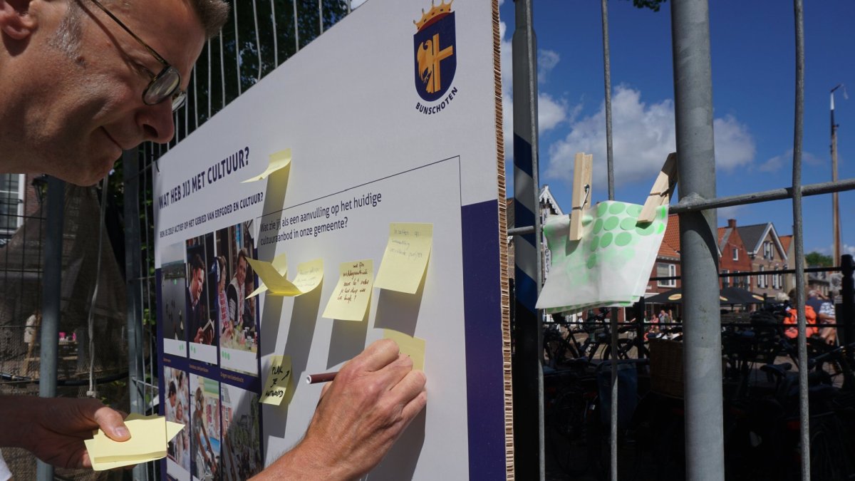 Bezoeker deelt input op participatiebord over kerkcultuur tijdens sessie in Bunschoten-Spakenburg, onderdeel van visieontwikkeling.