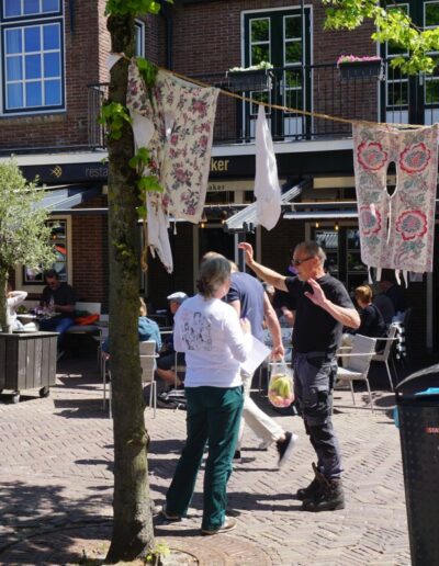 Informeel straatgesprek tussen bewoners tijdens MeeDenkDag in Bunschoten-Spakenburg, met waslijn en levendige dorpssfeer.