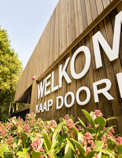 Entree van Conferentiecentrum Kaap Doorn, omgeven door bloeiende planten en bos