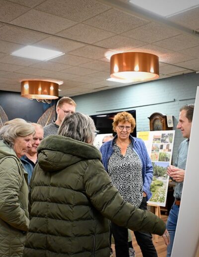Groepje volwassenen pratend bij een informatief displaybord tijdens de MeeDenkDag