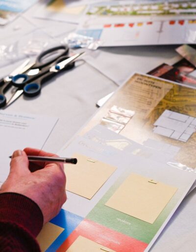 Tafel vol creatieve materialen zoals kaarten, notitiebladen, stiften en thee tijdens een ontwerpsessie voor Parkhaven 010 in Rotterdam, waarin deelnemers actief meedenken over de toekomst van het gebied.