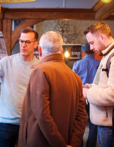 Drie mannen in gesprek met Michel Kolenbrander bij een informatieborden met plannen over de Spoorlaan in Oss. Foto: Wim Roefs